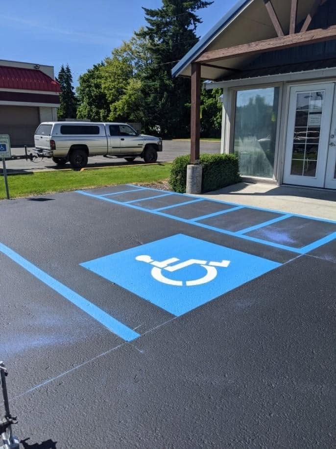 Blue accessible parking symbol and striped access aisle beside a commercial entrance.