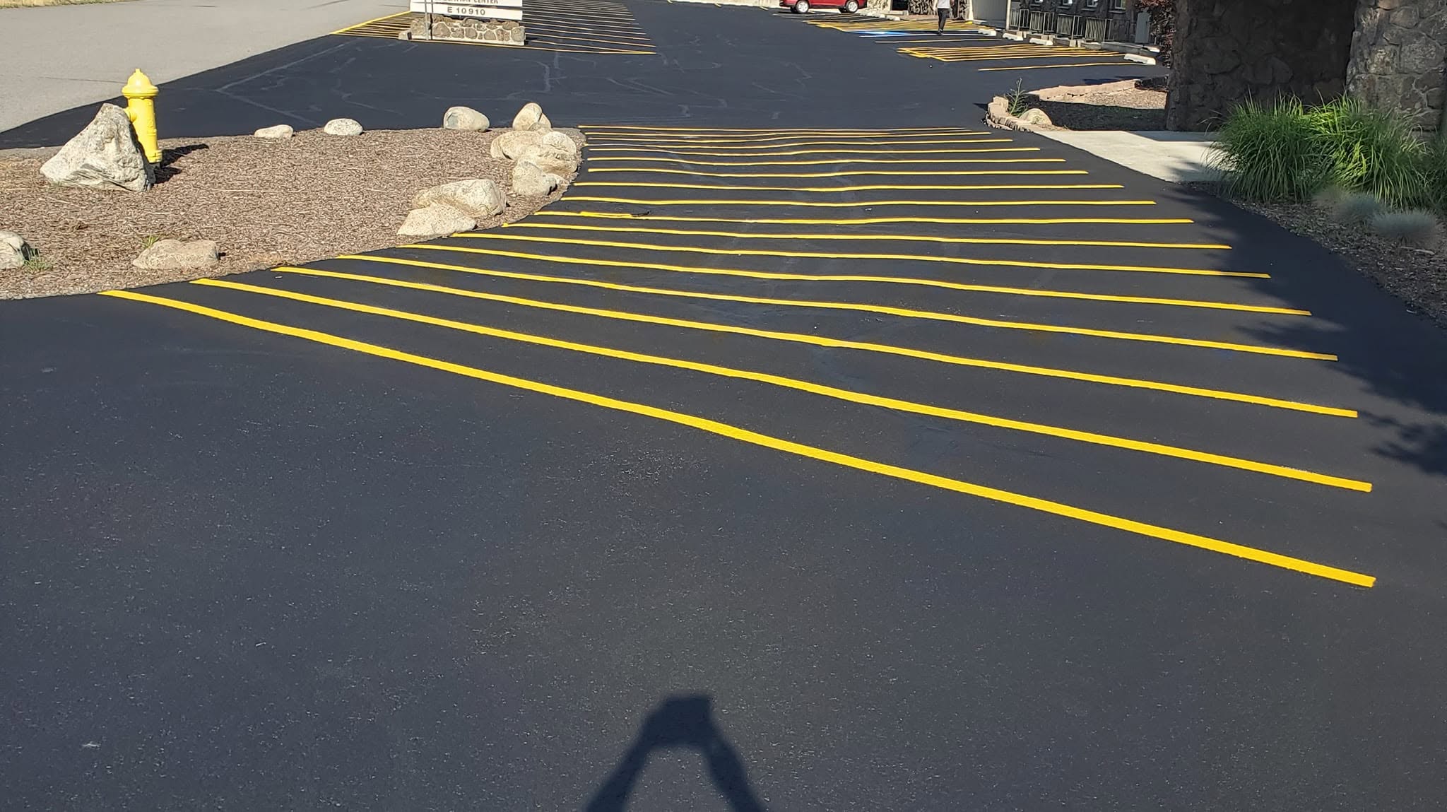 Yellow diagonal pavement markings on a dark asphalt surface.