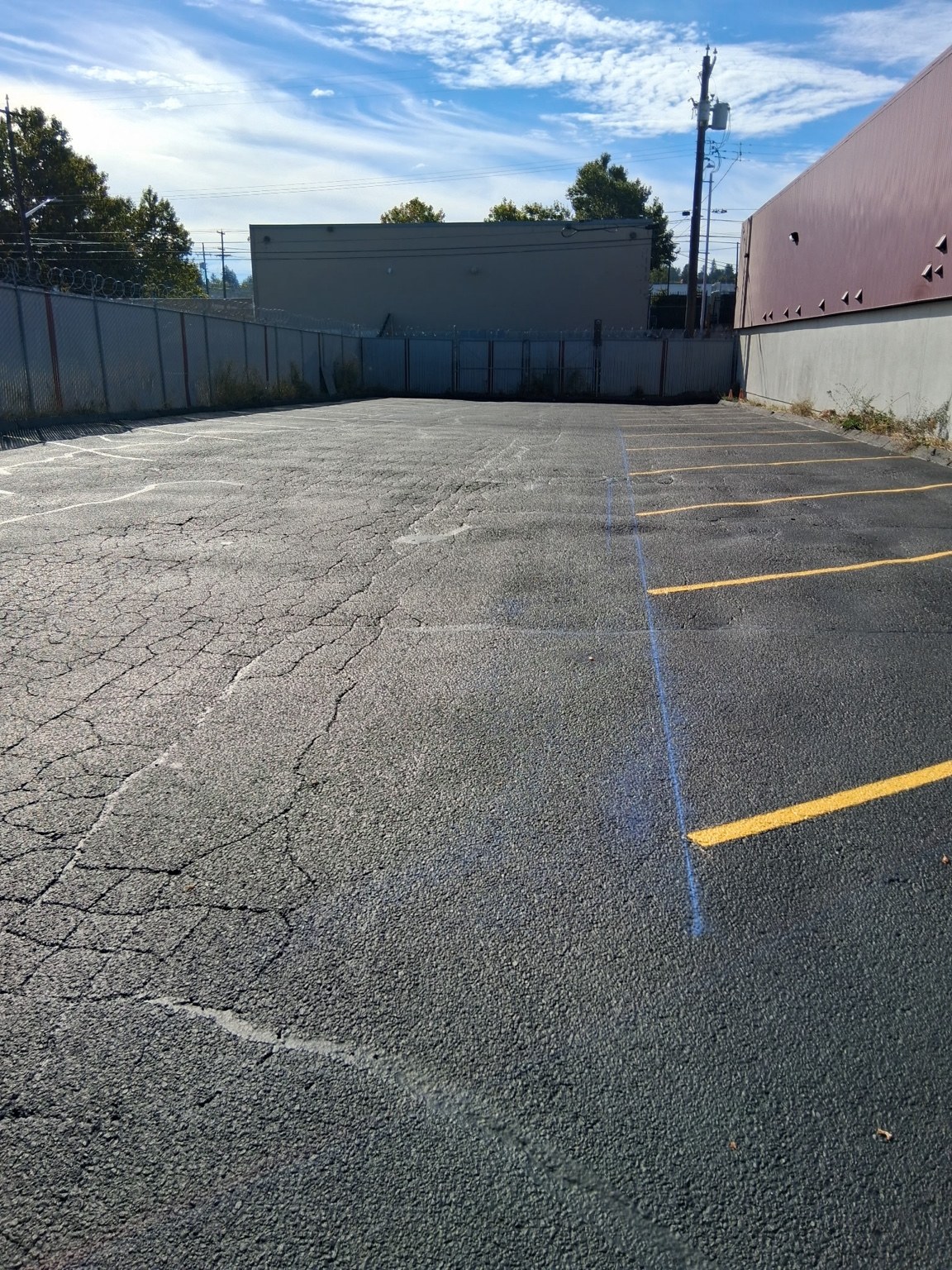 Commercial asphalt surface with yellow markings beside a building.